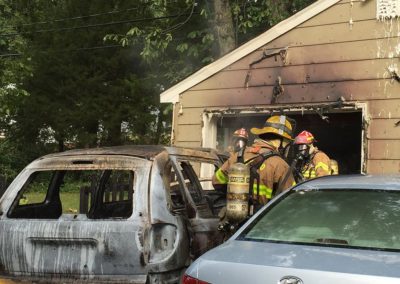 Firemen standing around a burned out car and garage from Henrico Fire Department Foundation in Glen Allen, VA
